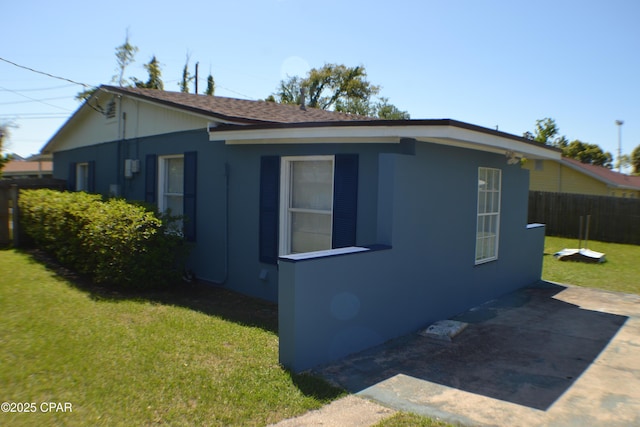view of property exterior featuring a yard, a patio area, and fence