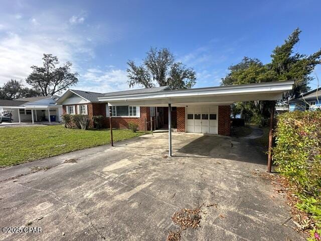 ranch-style house with a front lawn, an attached carport, concrete driveway, brick siding, and an attached garage