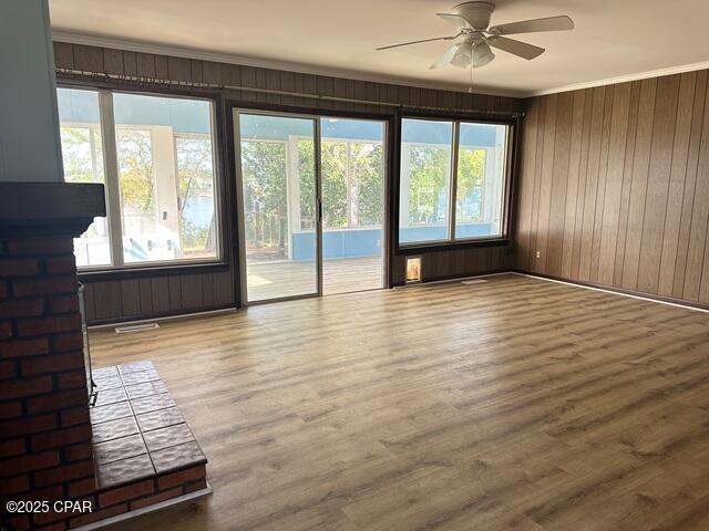 unfurnished living room featuring ceiling fan, a wealth of natural light, and wood finished floors