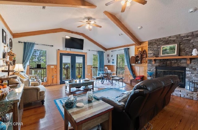 living area featuring hardwood / wood-style flooring, vaulted ceiling, a ceiling fan, and a fireplace