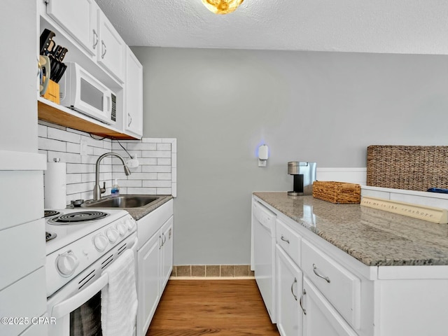 kitchen with tasteful backsplash, a sink, a textured ceiling, white appliances, and white cabinets