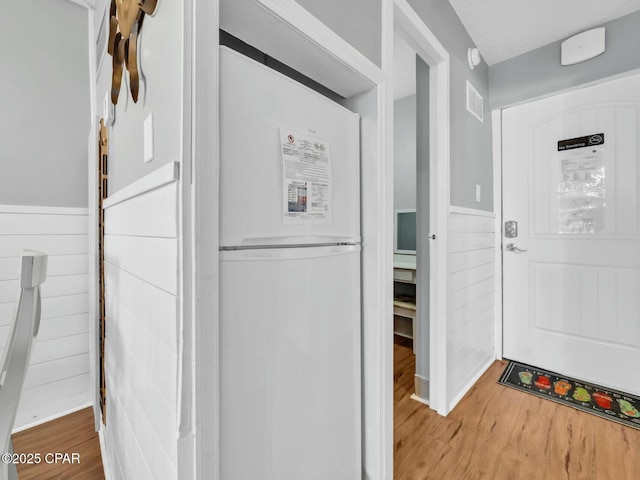 interior space featuring wood finished floors, visible vents, and a wainscoted wall