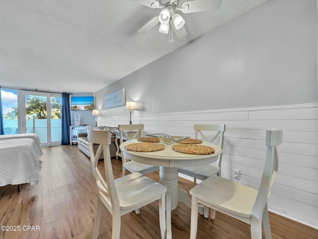 dining room featuring wainscoting, wood finished floors, a textured ceiling, and ceiling fan