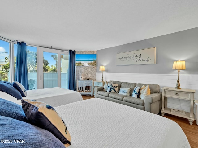 bedroom with a wainscoted wall, wood finished floors, and access to exterior