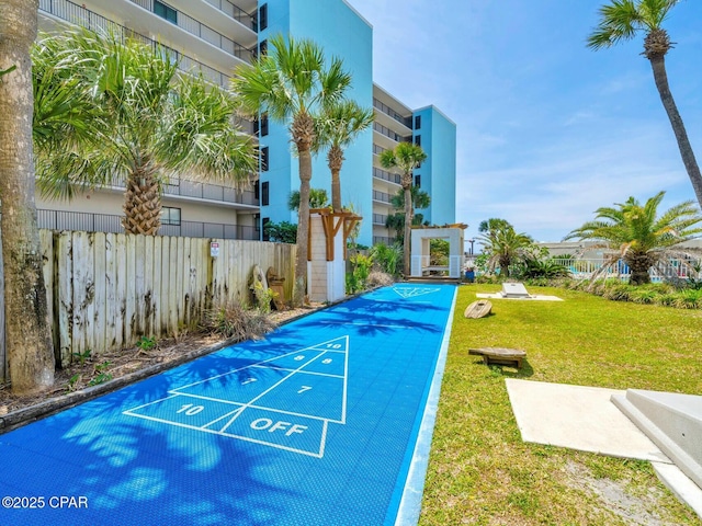 view of home's community with a lawn, shuffleboard, and fence
