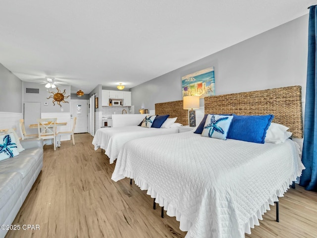 bedroom with a wainscoted wall, light wood-style floors, and visible vents