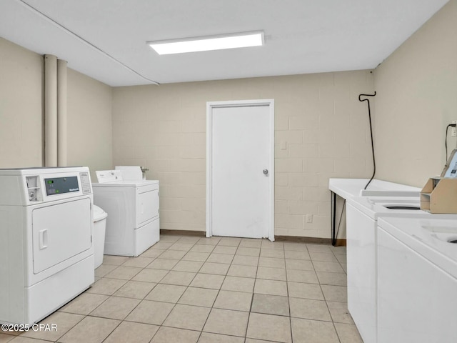 community laundry room featuring washer and dryer and concrete block wall