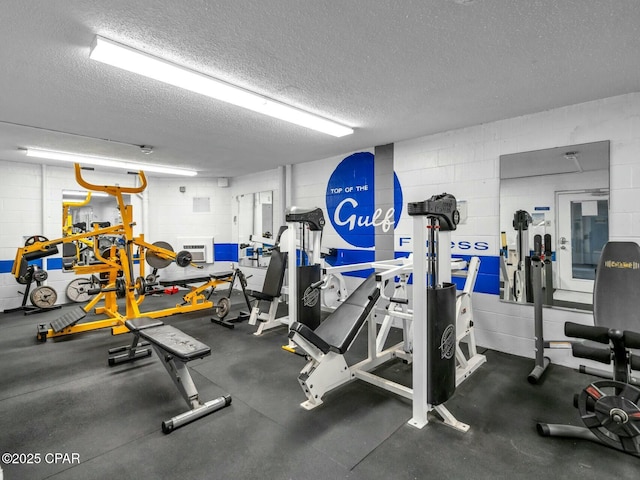 gym featuring concrete block wall and a textured ceiling