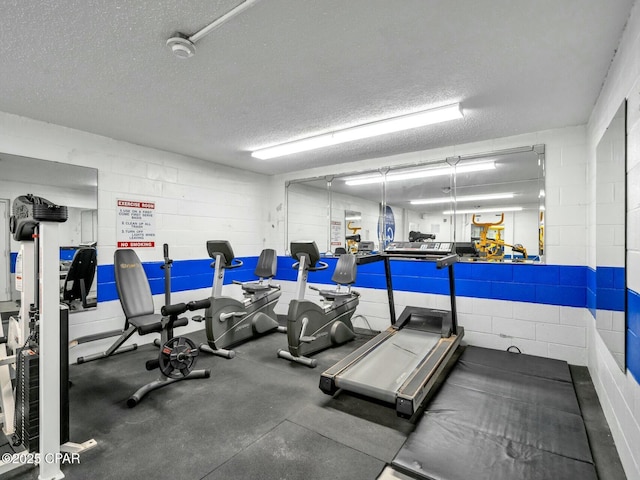 gym featuring concrete block wall and a textured ceiling