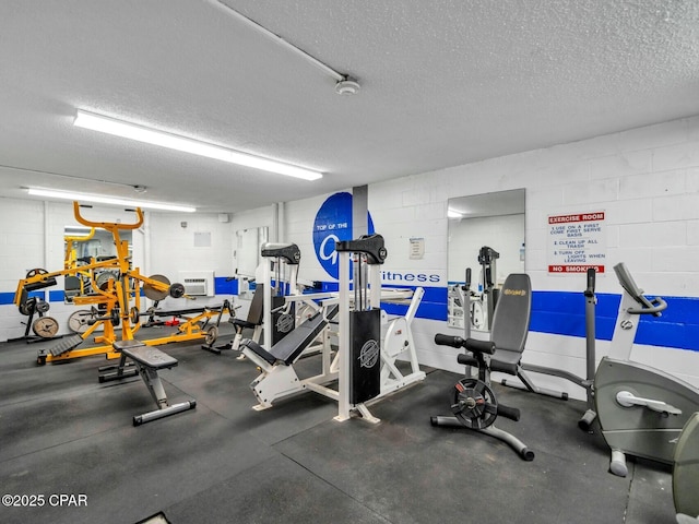 exercise room with a textured ceiling and concrete block wall