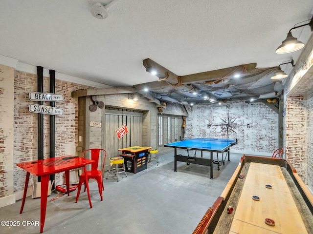 game room with concrete flooring, a textured ceiling, and brick wall