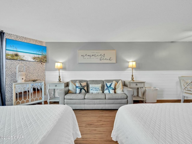 bedroom with wood finished floors and a wainscoted wall