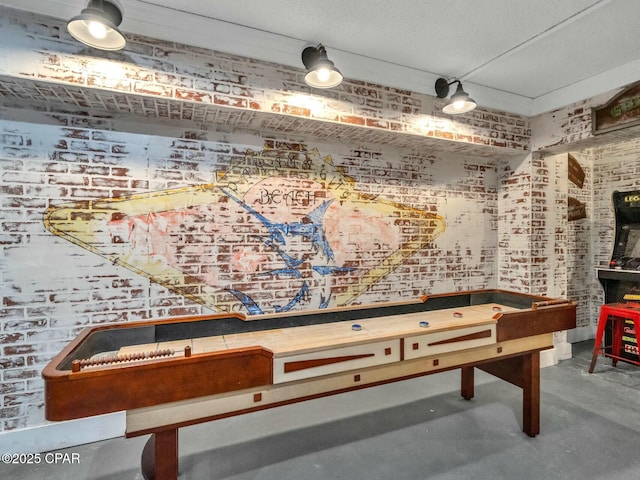 recreation room featuring brick wall and concrete floors