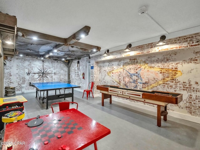 recreation room with brick wall and concrete flooring