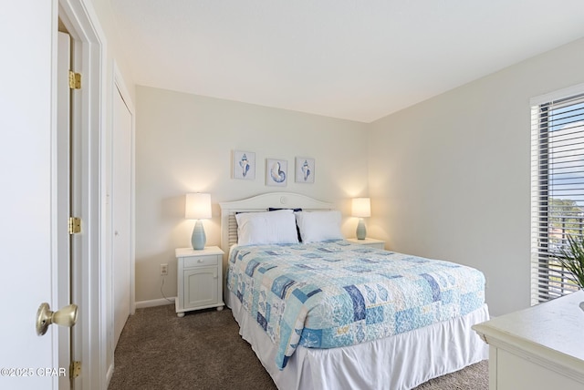 bedroom with dark carpet and baseboards