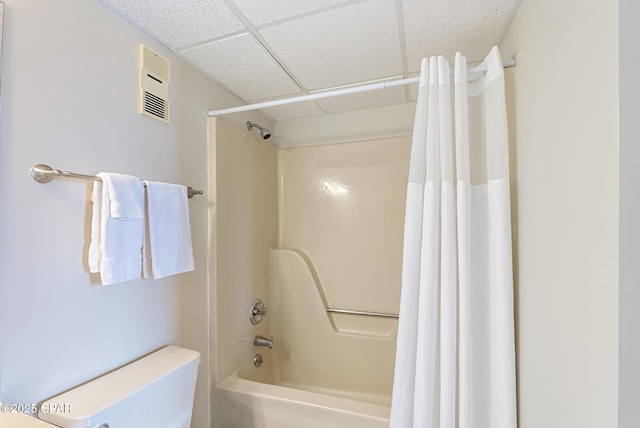 full bathroom featuring a drop ceiling, shower / bath combo, and toilet