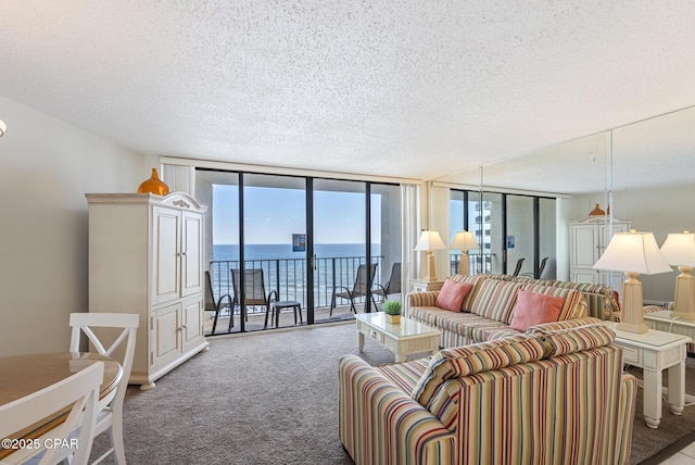 living area featuring a wall of windows, carpet floors, healthy amount of natural light, a water view, and a textured ceiling