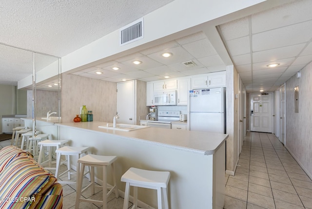 kitchen with white appliances, a sink, a peninsula, and a kitchen bar