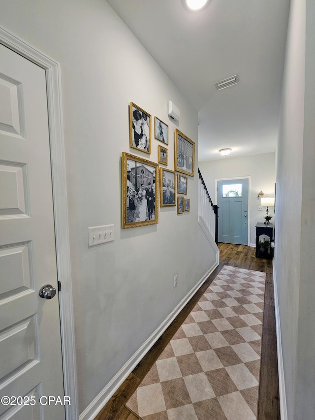 hall with baseboards, wood finished floors, visible vents, and stairs