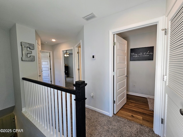 corridor featuring carpet floors, an upstairs landing, visible vents, and baseboards