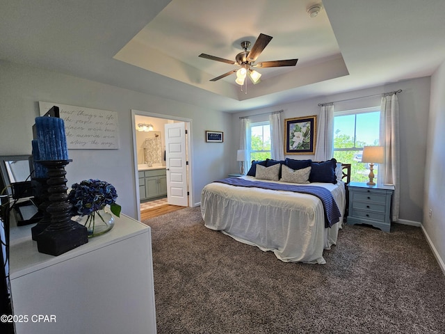 bedroom with baseboards, a tray ceiling, connected bathroom, and carpet flooring