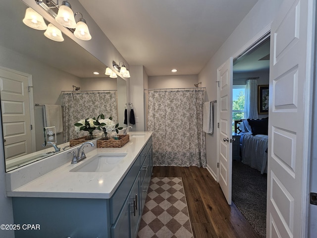 ensuite bathroom featuring recessed lighting, double vanity, wood finished floors, a sink, and ensuite bath