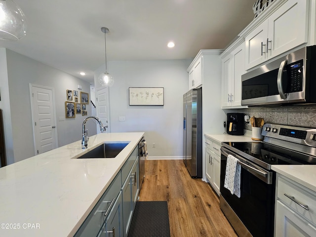 kitchen featuring white cabinets, stainless steel appliances, a sink, recessed lighting, and backsplash