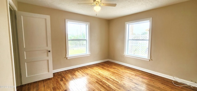 empty room with plenty of natural light, hardwood / wood-style flooring, baseboards, and a textured ceiling