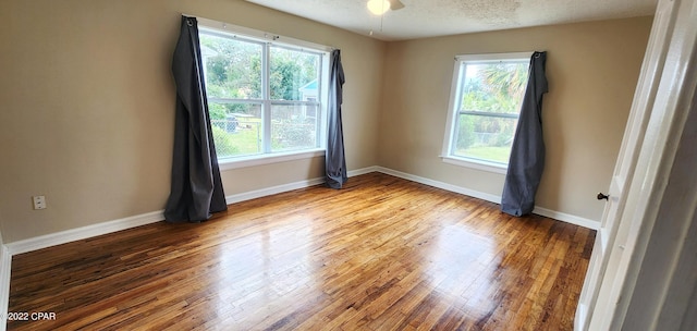 empty room with plenty of natural light, hardwood / wood-style floors, and baseboards