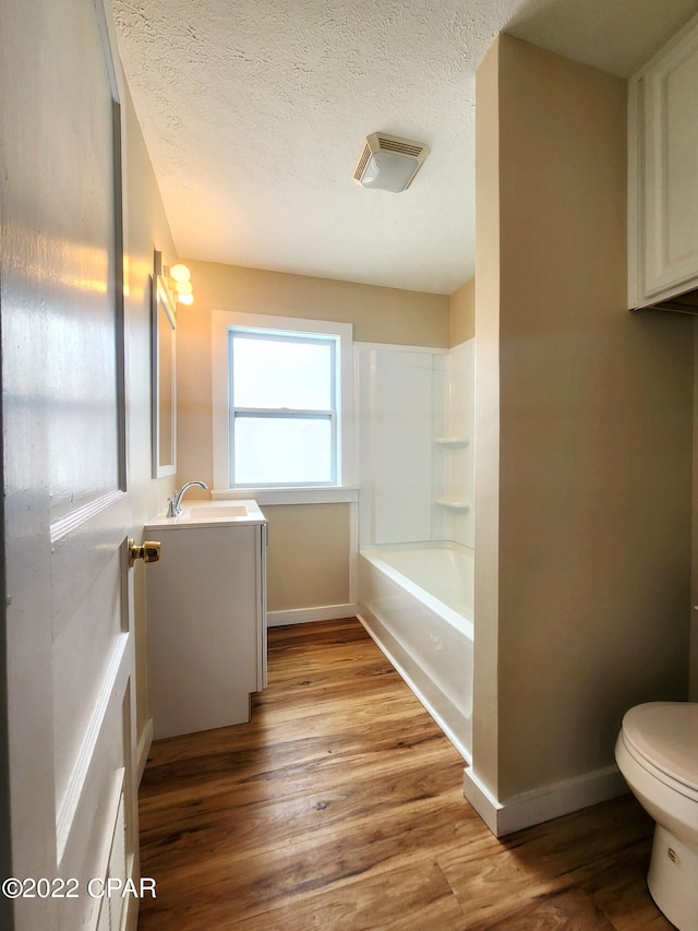 full bathroom featuring a textured ceiling, toilet, visible vents, wood finished floors, and vanity