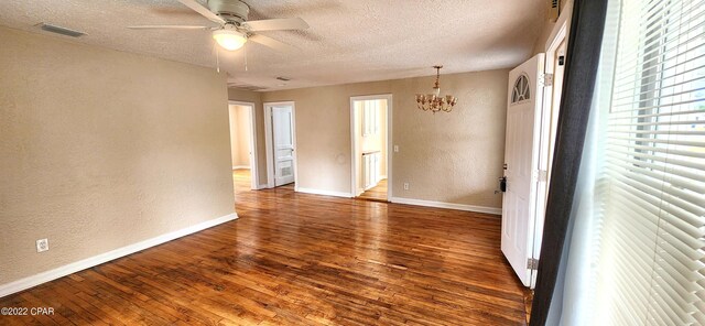 unfurnished room with hardwood / wood-style floors, a textured wall, visible vents, baseboards, and a textured ceiling