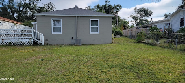back of house featuring a yard, central AC, a shingled roof, and fence