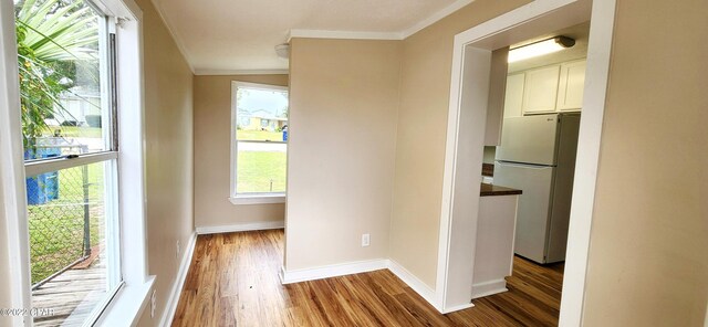 hallway featuring baseboards, wood finished floors, and ornamental molding