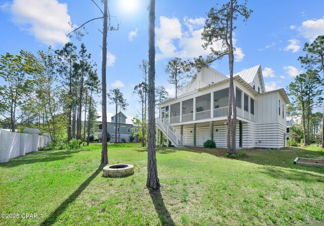 205 Mallard Ln, Santa Rosa Beach, FL 32459 - rear view of house with stairs, a yard, board and batten siding, a fire pit, and a sunroom