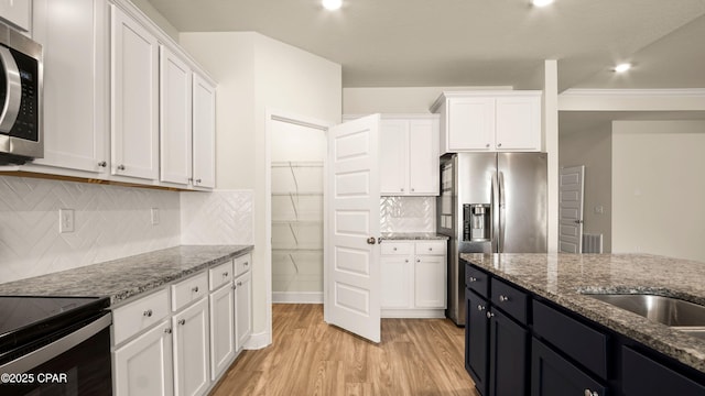 4744 Rosemary St, Panama City, FL 32404 - kitchen featuring light wood finished floors, stainless steel appliances, white cabinetry, and light stone counters