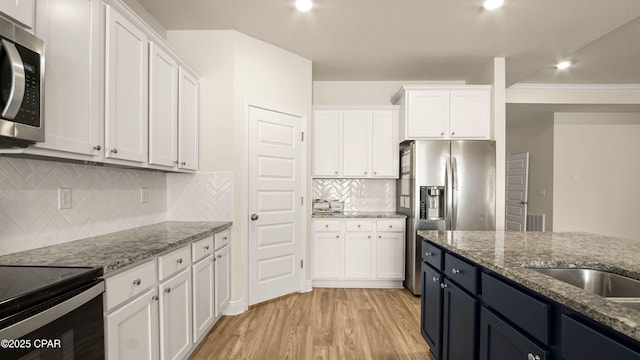 4744 Rosemary St, Panama City, FL 32404 - kitchen with light stone counters, light wood-type flooring, white cabinetry, and stainless steel appliances