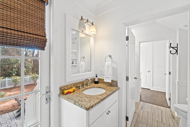 bathroom with toilet, ornamental molding, and vanity