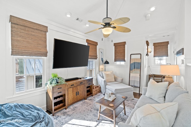 living area with baseboards, a ceiling fan, light wood-type flooring, and visible vents