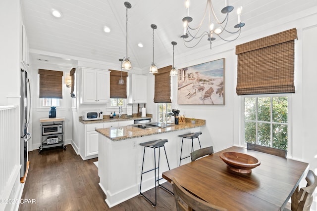 kitchen with a sink, white cabinetry, a peninsula, and white microwave