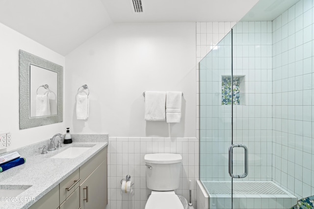 full bathroom with visible vents, toilet, tile walls, a sink, and a stall shower