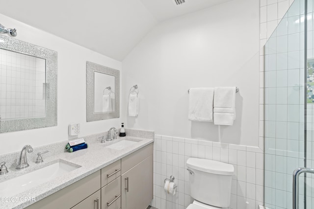 bathroom featuring double vanity, toilet, tile walls, and a sink