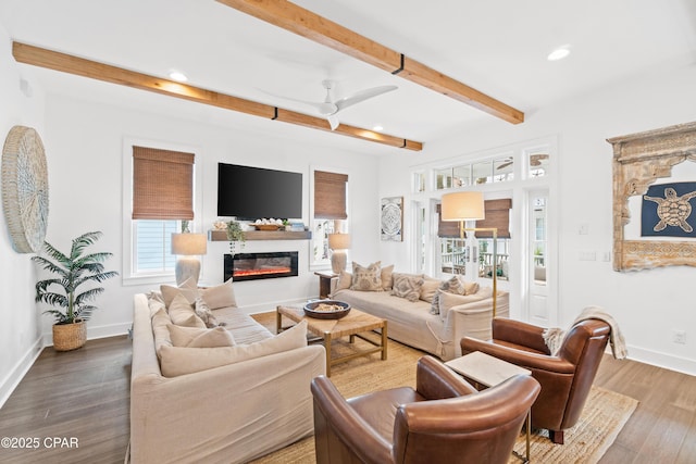 living room with beam ceiling, a glass covered fireplace, recessed lighting, baseboards, and wood finished floors