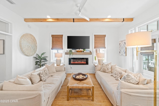 living room with ceiling fan, a glass covered fireplace, recessed lighting, beamed ceiling, and visible vents