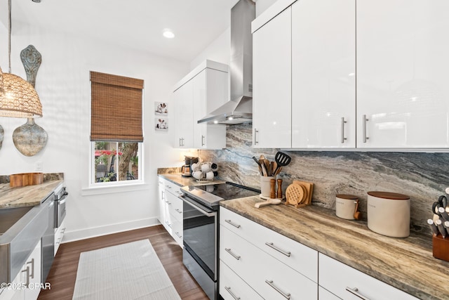 kitchen featuring baseboards, white cabinetry, wall chimney exhaust hood, tasteful backsplash, and stainless steel range with electric cooktop