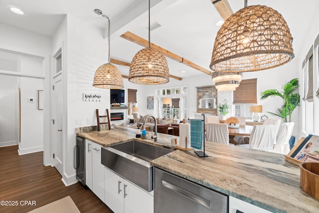 kitchen featuring light stone counters, a sink, dark wood-type flooring, stainless steel dishwasher, and visible vents