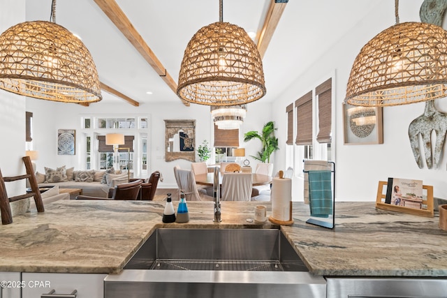 kitchen with stone countertops, open floor plan, a notable chandelier, and beamed ceiling