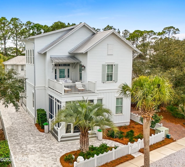 view of front facade with decorative driveway, a fenced front yard, and a balcony
