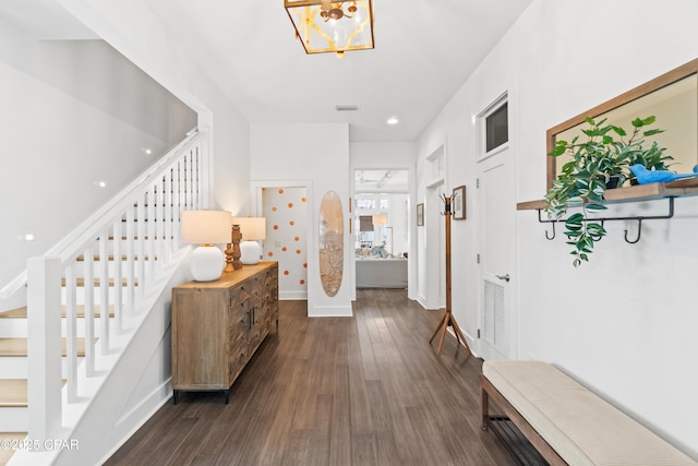 corridor featuring visible vents, stairs, baseboards, dark wood-style floors, and a notable chandelier