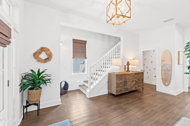 entryway featuring visible vents, wood finished floors, stairway, baseboards, and a notable chandelier
