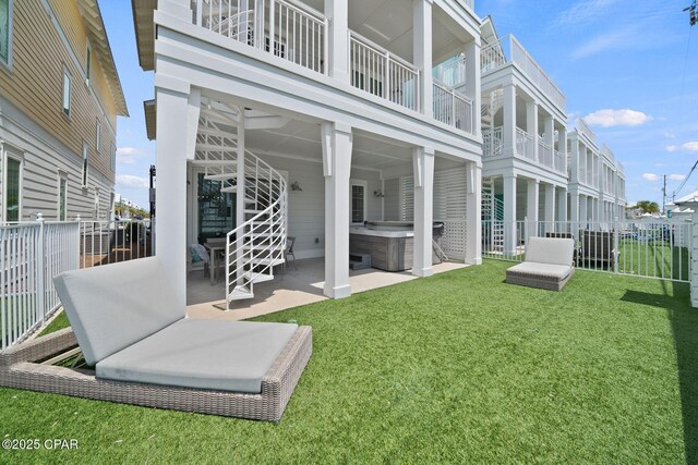 rear view of property featuring a yard, fence, a hot tub, and a patio area